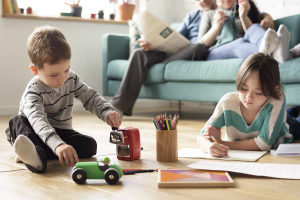 Children playing in the living room while a an adult is reading the paper